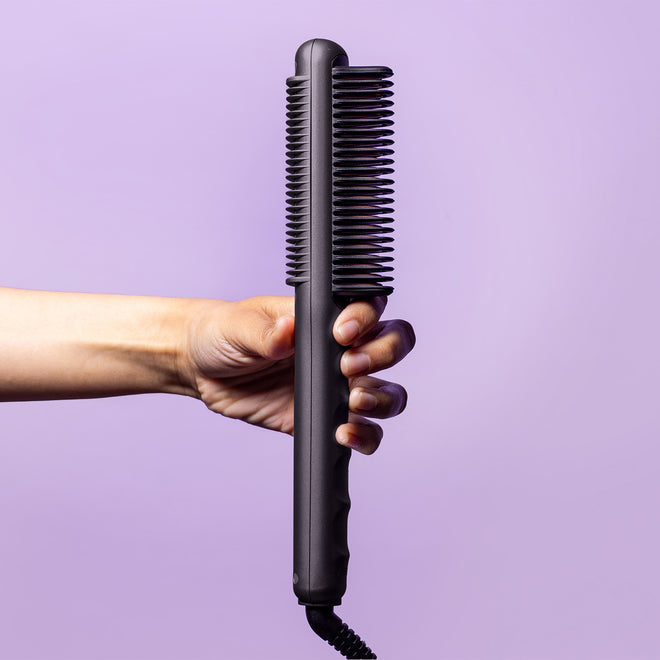 Hand-holding-black-glider-pro-heated-styling-comb-on-a-white-background